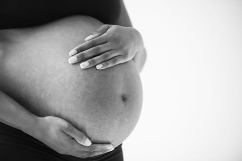 View of just a woman's pregnant belly with her hands holding on gently