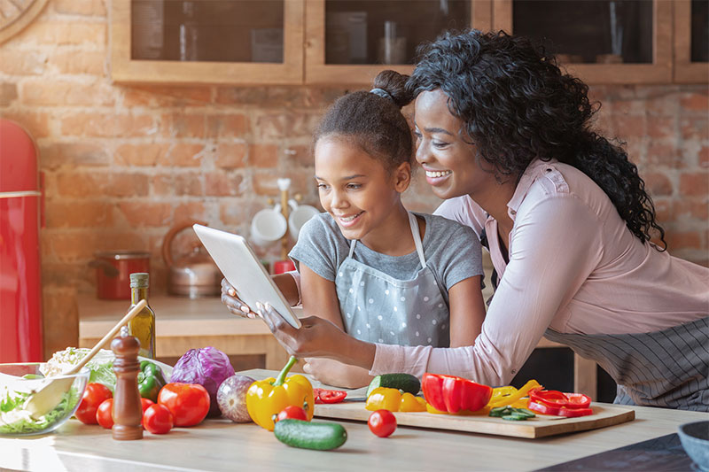 Mom and daughter read recipe on tablet while cooking Mom and daughter read recipe on tablet while cooking