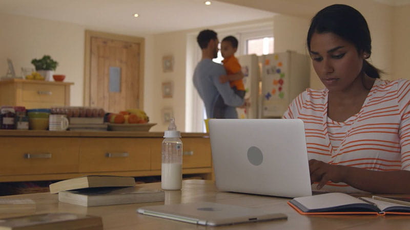 mother working on a laptop at the kitchen table
