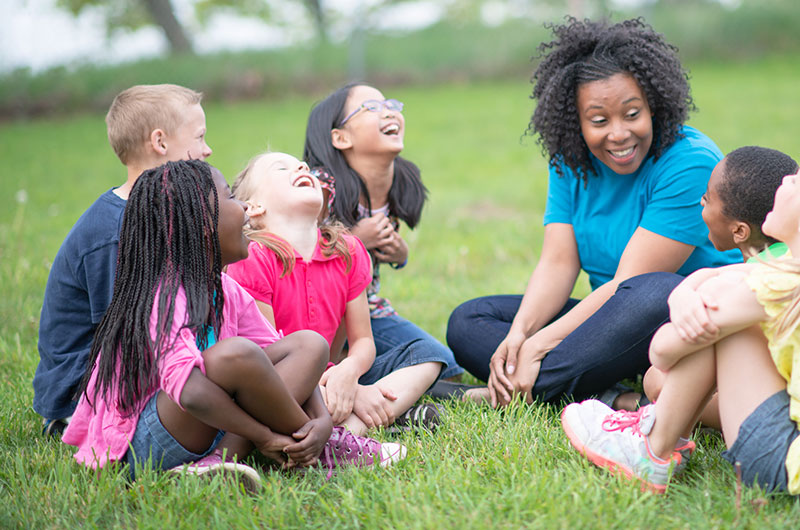 teacher with young children sitting in a circle outdoors teacher with young children sitting in a circle outdoors