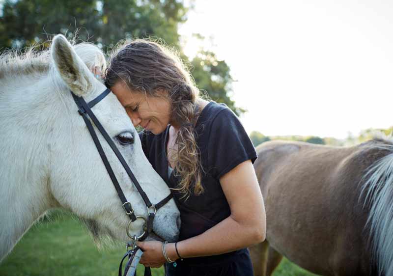 women leaning face to face with a horse